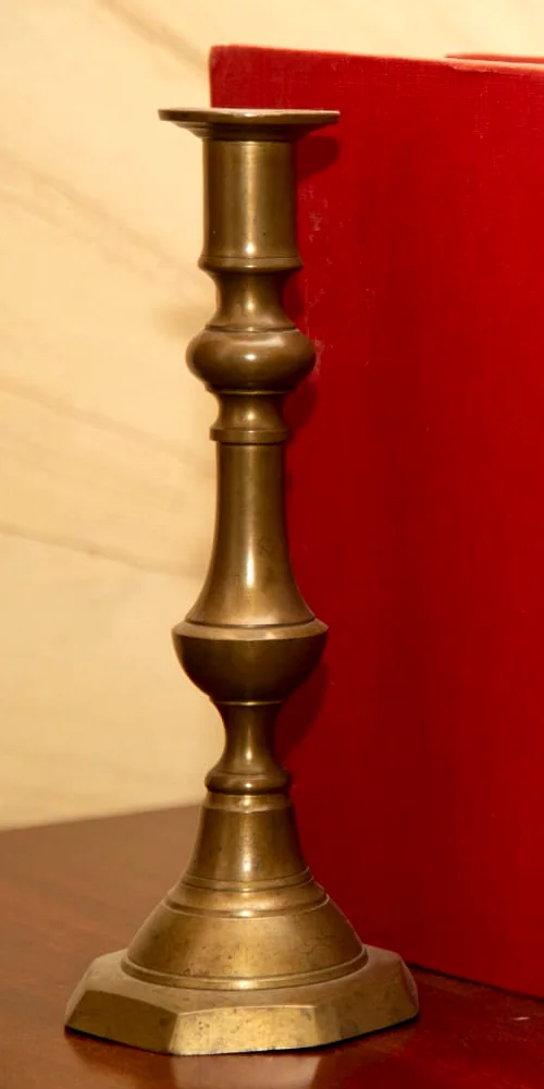 Candelabro de latón y un volumen antiguo en la biblioteca de la firma